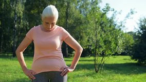 Nice sporty elderly woman doing stretching exercise outdoors