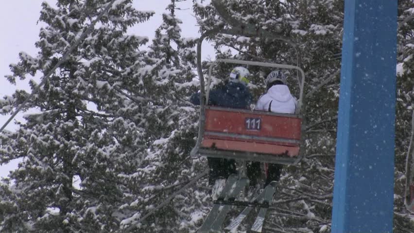 A funicular in the mountains lifts tourists and skiers to the top of the ski slope, snowfall and wind.