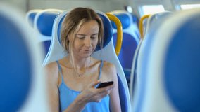 Young woman smiling and using smartphone in the train. Technology and internet concept
