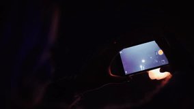 A woman shoots fireworks on a smartphone. The lights are beautifully reflected in her glasses. 4k 10 bit video