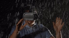Young man playing game in virtual reality glasses in the rain. VR Technology concept.
