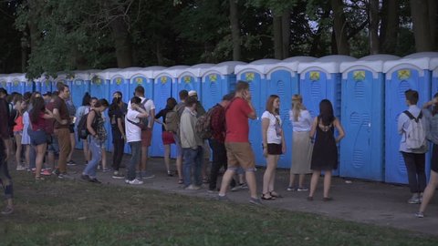 Kiev, Ukraine, June 2017: People stand near bio toilets installed in the venue of the music festival