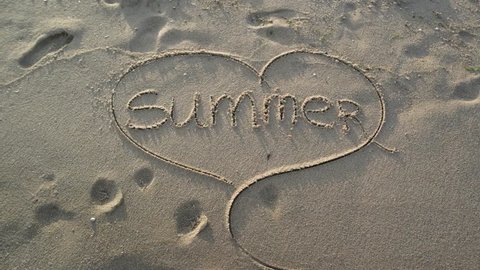 Sea wave covering word summer and drawing of a heart written in sand on beach