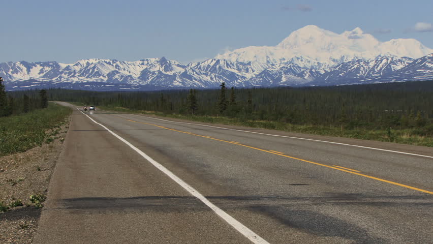 A person on a solo motorcycle tour passing Denali (Mt. McKinley) in Alaska, on