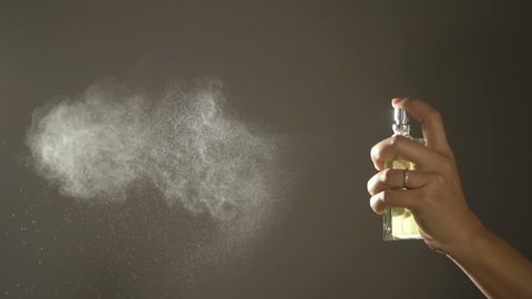 Slow motion,Woman spraying fragrance with scent particles.
