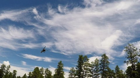 TUSAYAN, AZ/USA: August 1, 2017- Tracking shot of a low flying tourism helicopter as it passes overhead. Clip reveals a chopper silhouetted against an illuminated cloudy sky.