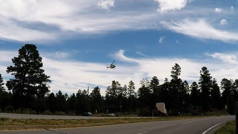 TUSAYAN, AZ/USA: August 1, 2017- Tracking shot of a helicopter returning to the Grand Canyon National Park airport. Clip reveals a chopper flying low over the tree line.