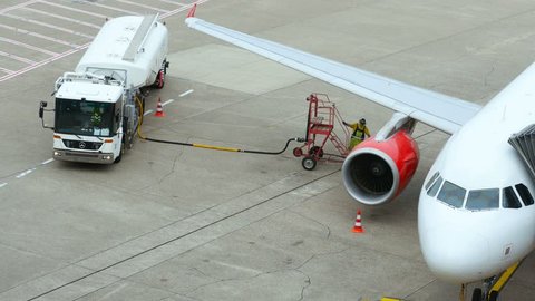 DUSSELDORF, GERMANY - JULY 21, 2017: Top view of airport service man take the fuel hose and move it to the aircraft wing. Use the stairs.