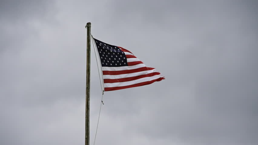 American flag in a stiff breeze, flapping and tattered becaue of exposure