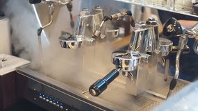 Closeup tilt down of coffee shop barista activating espresso machine steam wand to by turning steam valve knob.High quality coffee clip video.