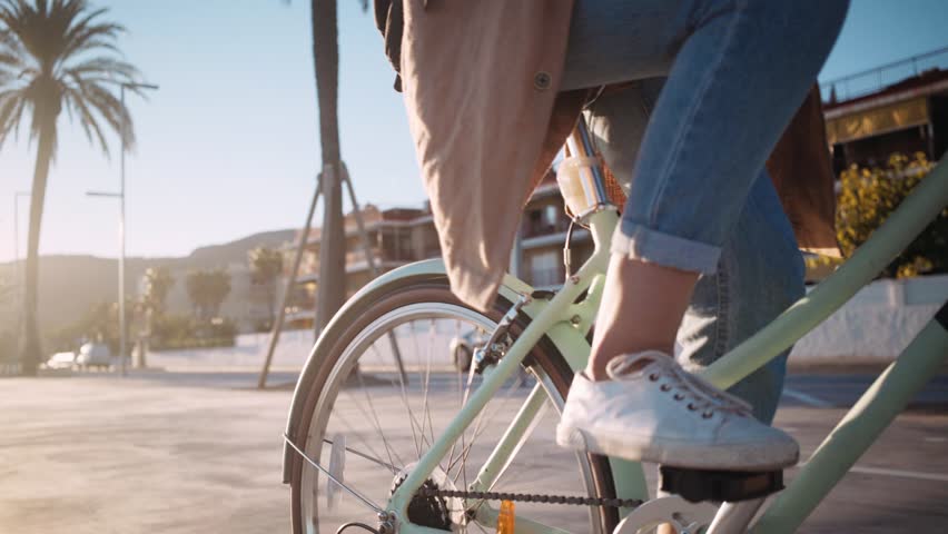 Beautiful summertime mood shot of young woman or girl riding bicycle through beach promenade, in stylish outift, pedalling next to palm trees in sunset light, concept youth and miami Royalty-Free Stock Footage #31052050