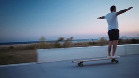 Unconventional millennial hipster extreme sports athlete with tattoos rides longboard on boardwalk next to beach during twilight sunset hour, enjoys youth and freedom - Powered by Shutterstock - Get 15% off with code: PIKWIZARD15