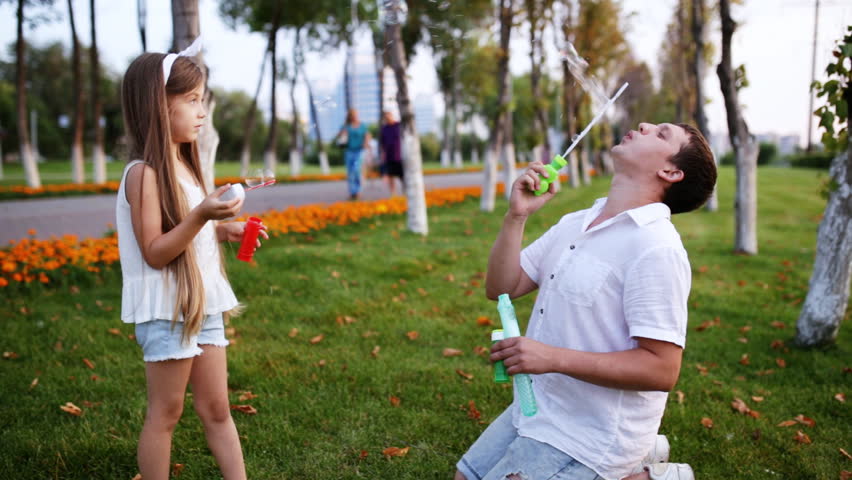 little girl blowing soap bubbles on the lawn