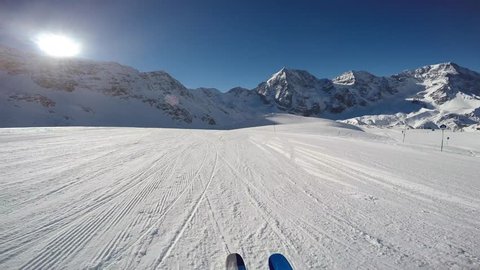 Skiing along a snowy ridge. In background blue cloudy sky and shiny sun and Tre Cime, Drei Zinnen in South Tirol, Dolomites, Italy. Adventure winter extreme sport. POV Camera.