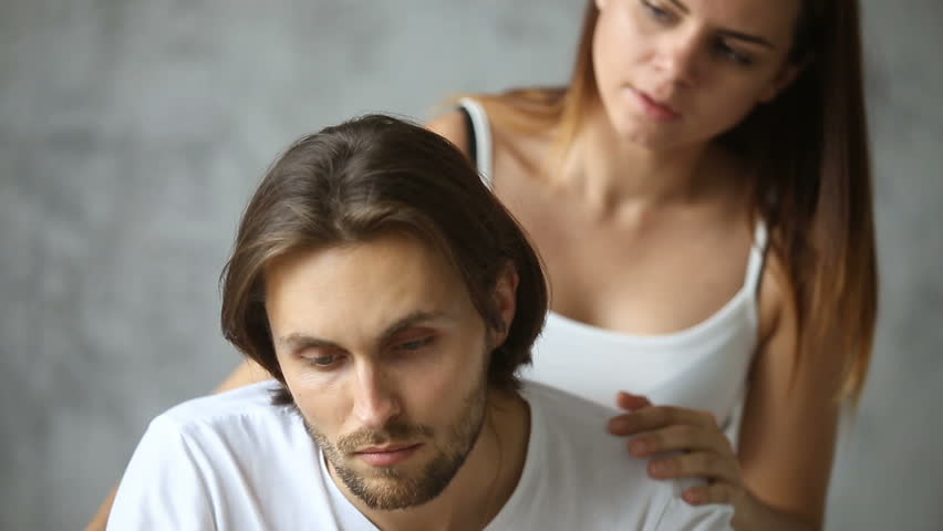 Annoyed angry man feels offended after conflict, rejecting woman trying to make peace cheering him up, avoiding girlfriends touch looking away sitting on bed, apology not accepted, leave me alone