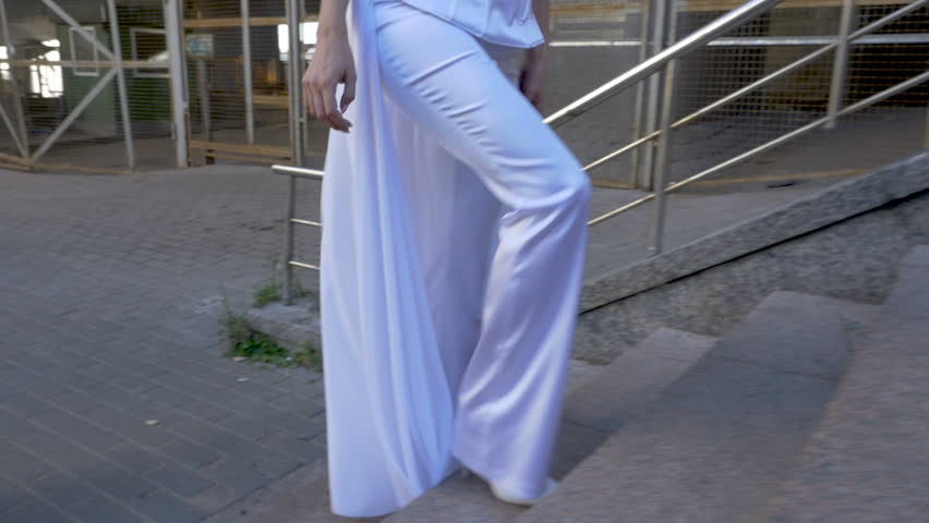 A woman in a white suit climbs the stairs.