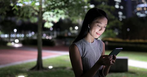 Woman listen to music on cellphone at night 