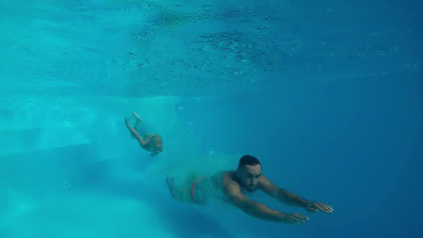 Underwater swimming.
Father and son swimming together under water in swimming pool. | Shutterstock HD Video #31063258