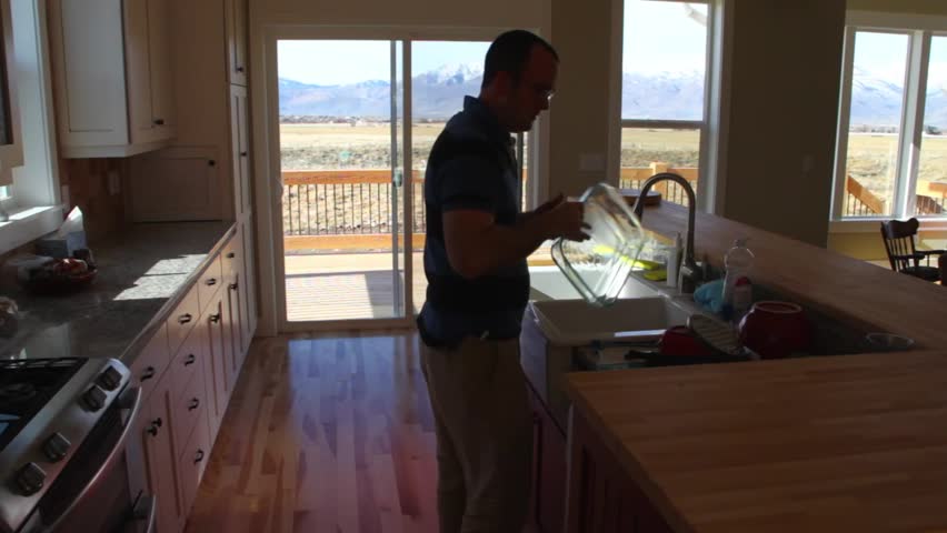 A man puts away dishes in a new kitchen