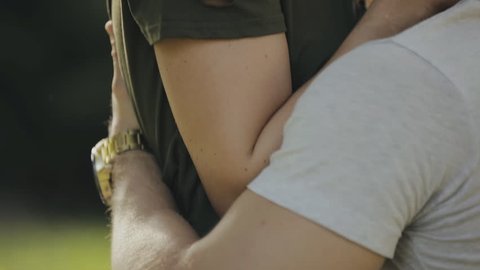 Happy young couple embrace sitting on grass in park, slowmotion