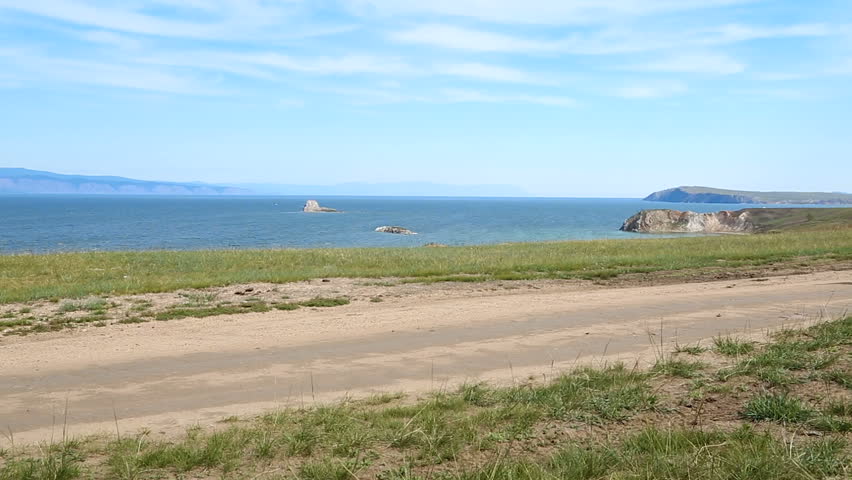 Hiking woman with backpack trekking along blue lake Baikal. Caucasian girl living active lifestyle