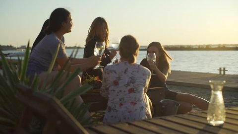 Young girls talking drinking  wine beach party seaside sunrise rapid slow motion