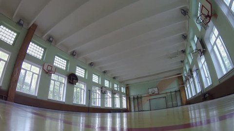 Light turning on in empty school gym with volleyball net.