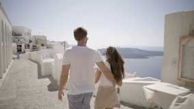 4k travel video, couple walking in fira village of santorini island on sunny summer vacation day
