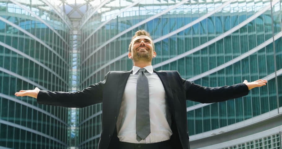 a black man dressed in a business suitcase under a skyscraper exults for a successful deal or for a personal work success.
Man is happy with success and have passion for business in finance.