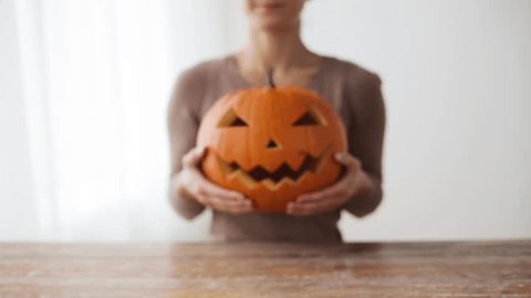 halloween, decoration and holidays concept - close up of woman with carved pumpkin or jack-o-lantern at home