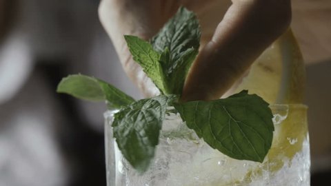Barman decorates a cold cocktail with herbs