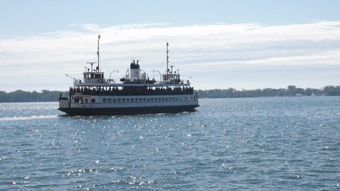 Slow motion view of public ferry, Sam McBridge leaving Toronto for the Toronto islands. Sparkling water. Summer in Toronto.
