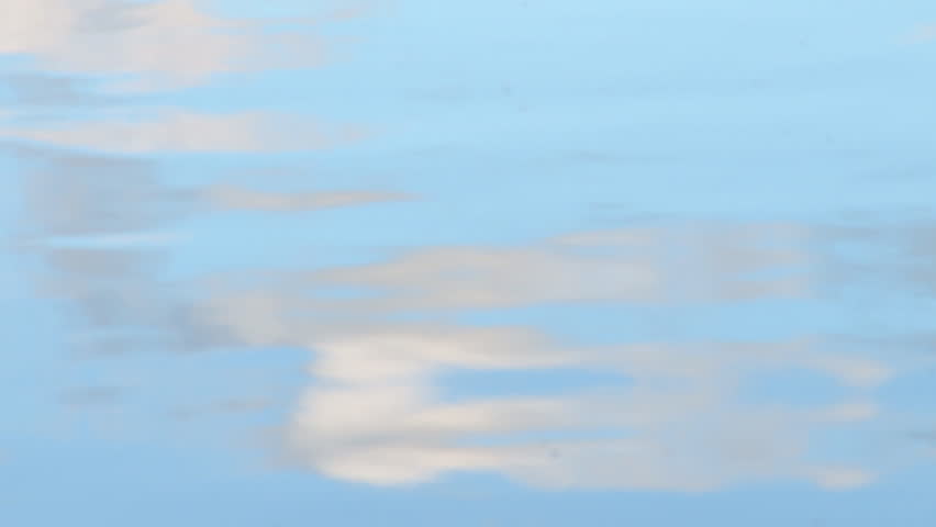 Sky and clouds reflected on smooth undulating water.