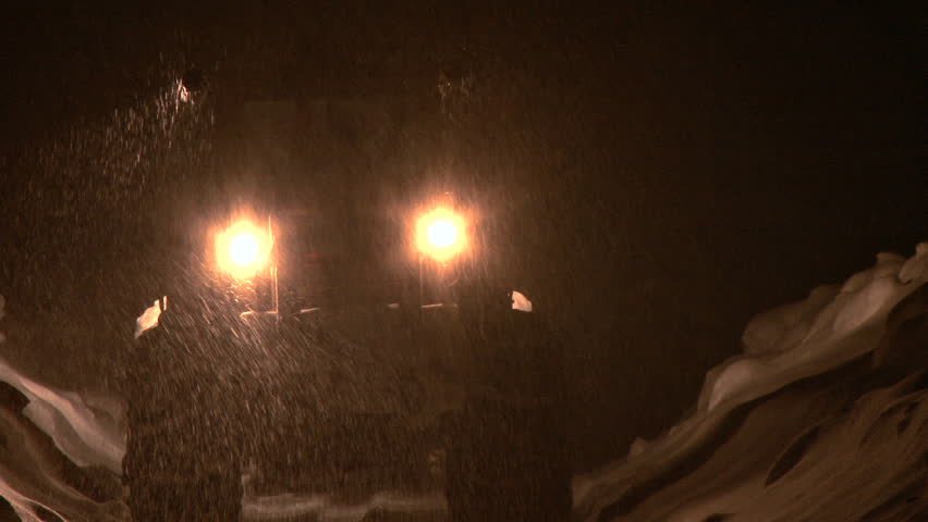 Loader moves away from camera through blizzard