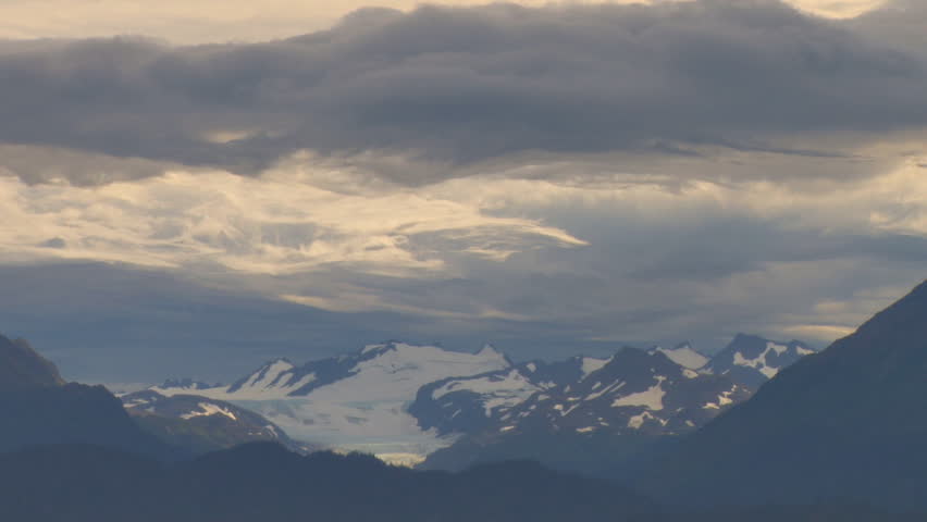 Intricate lace work of woven storm clouds writhe over the mountains and glacier.