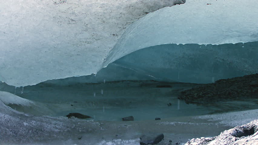 Close-up of a small ice cave with dripping water and gravel at the nose of Exit