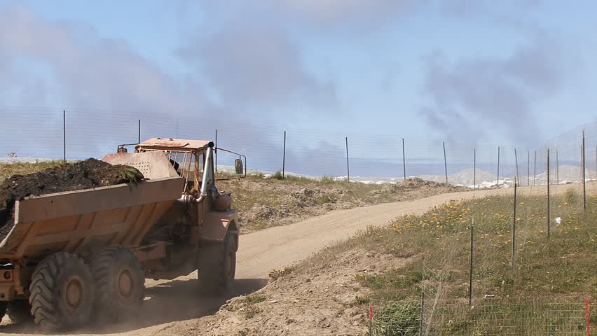 A very solidly-built dump truck crawling up a hill with a load of freshly dug