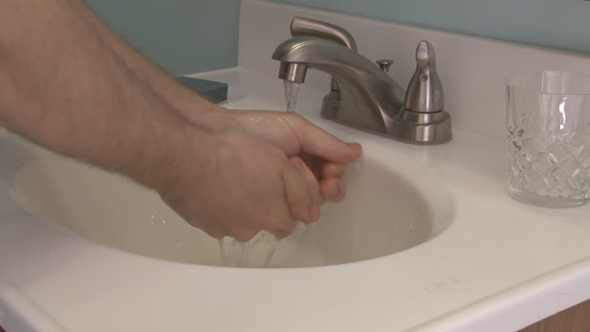 Caucasian man washes hands in a bathroom sink
