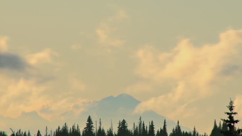 Fast flowing cumulus clouds zooming past Mt. Redoubt in the late afternoon, a