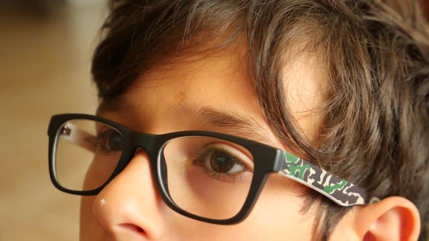 the boy in glasses looks into the distance. his eyes are moving. 4k close-up. Slow motion. copy space