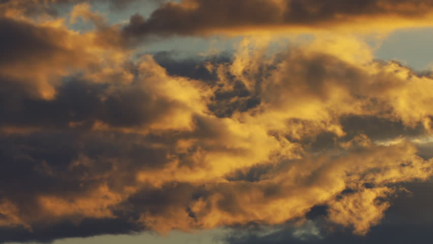 Dynamic glowing clouds of sunset, golden light fading.