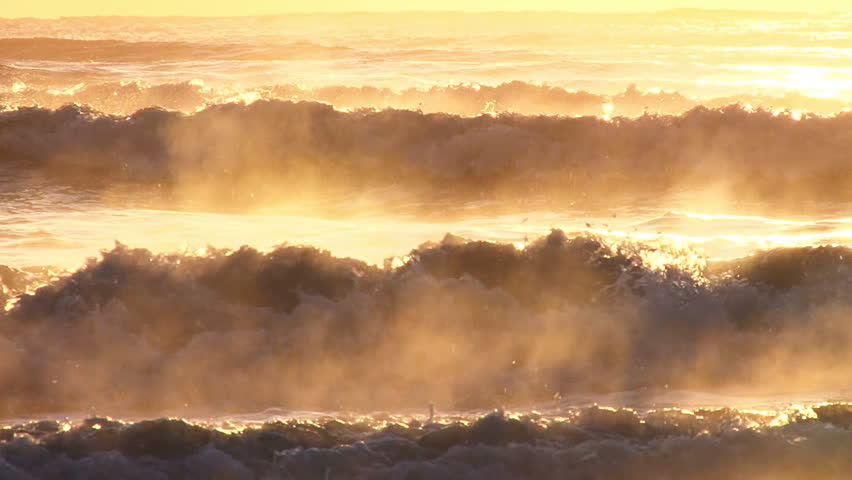 Telephoto shot of surf and spray glowing in golden late afternoon sun.