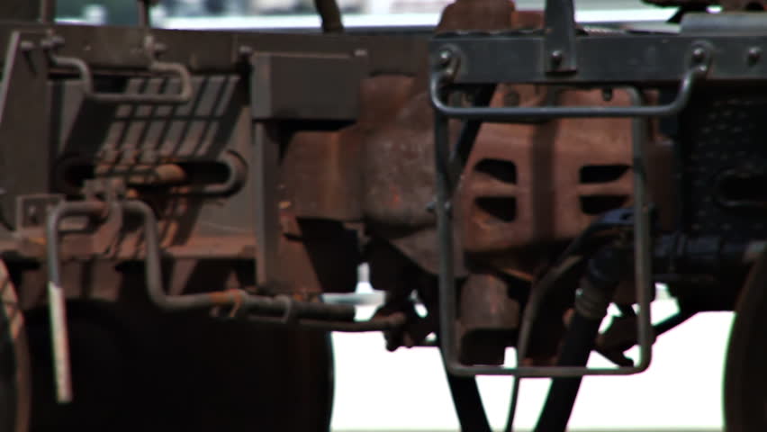Close-up of a hitch coupler as a freight train of tank cars rolls by.