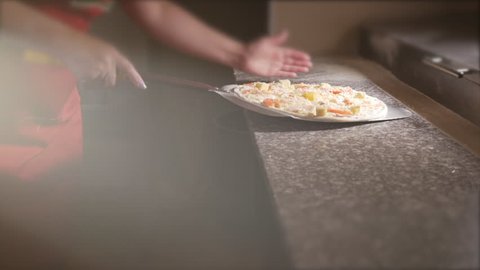 The cook puts pizza on a shovel to put pizza in the oven. 4K.