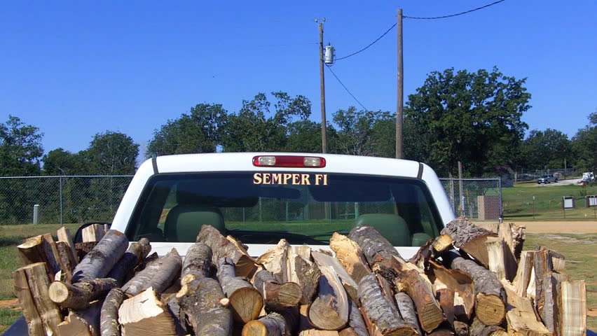 A rick of firewood in the back of a pickup truck.
