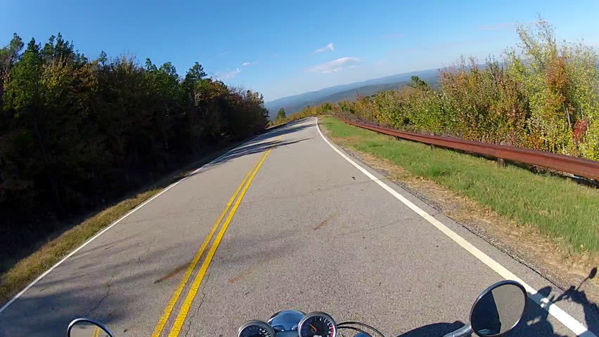 A helmet cam point of view shot of a motorcycle speeding down a forested