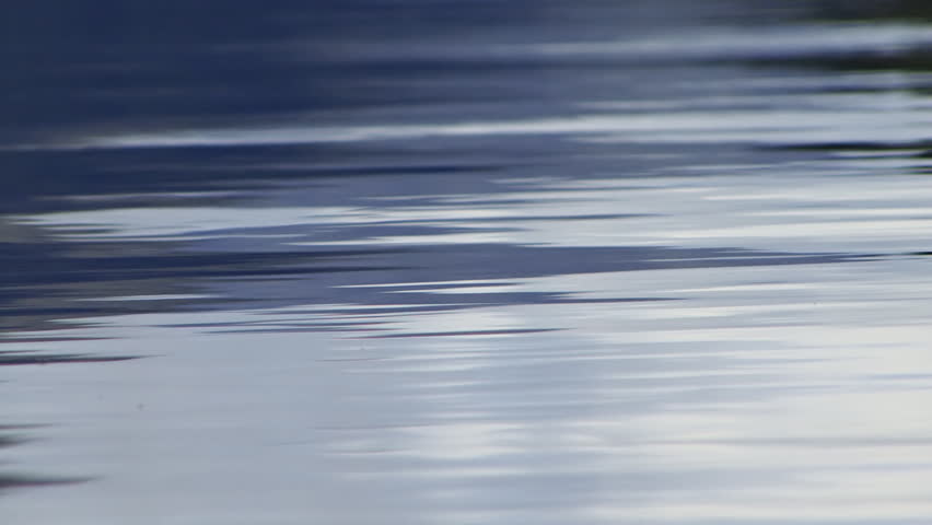 Low angle shot of mountain reflections on a blue-gray lake water surface.