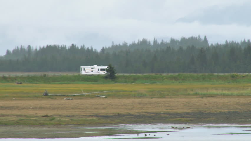 An RV travels along the Slough Road across Beluga Slough. Cloudy day.