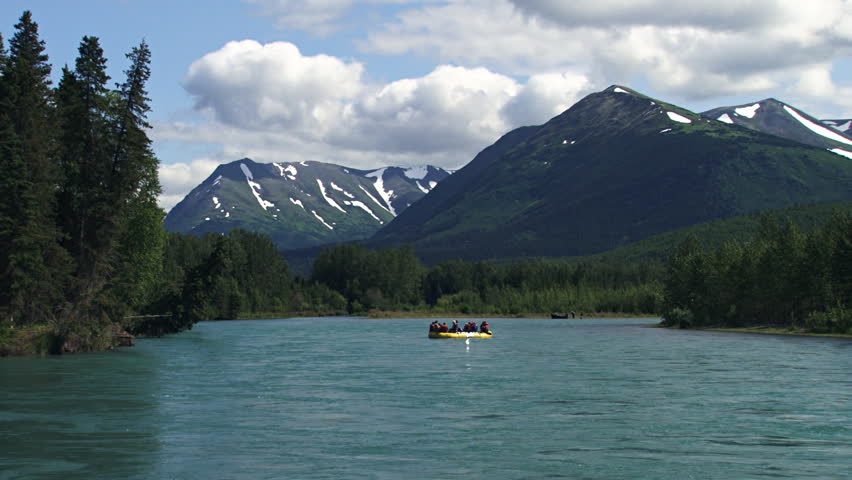 A group of travelers relaxing on a yellow inflatable raft as it floats down the Kenai River in Alaska in early August.