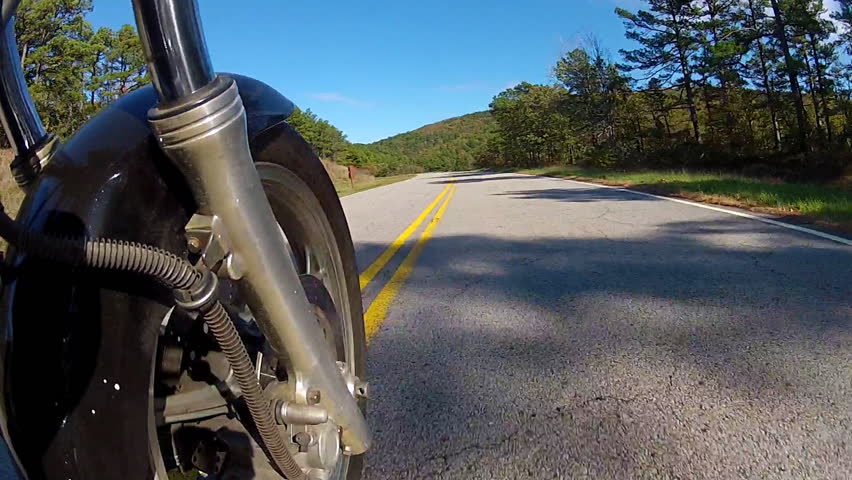 A low angle point of view shot of a motorcycle speeding down a curing and
